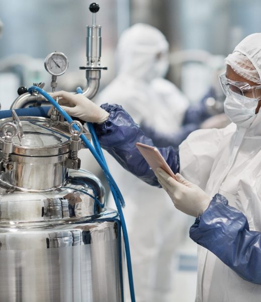 Portrait of female worker wearing protective suit while operating equipment at modern chemical plant, copy space